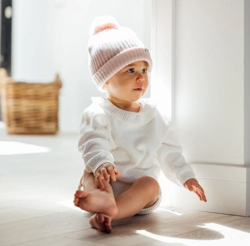 Baby wearing cut and sew knitted beanie hat and fully fashioned jumper
