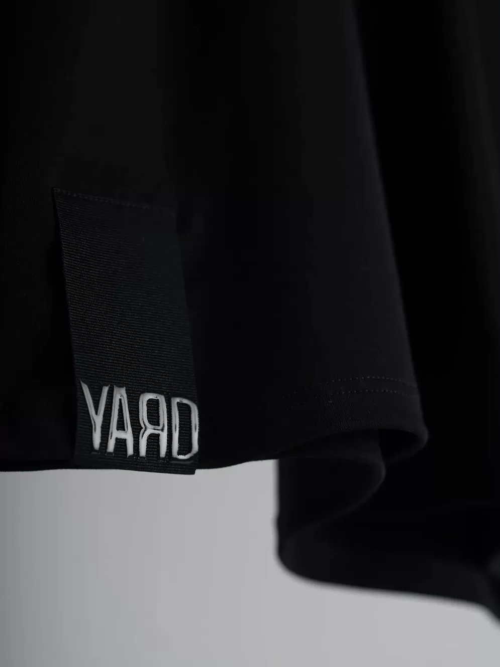 Black t-shirt with cotton twill hem label with "YARD" silicone logo black on black